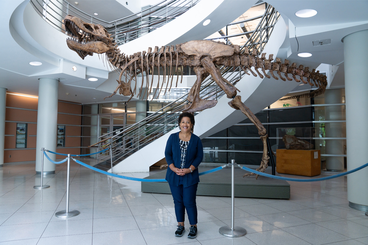 Lisa White standing in front of a Trex fossil