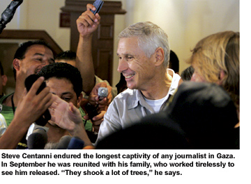A smiling Steve Centanni, just released by his captors, is surrounded by reporters with microphones and well wishers.