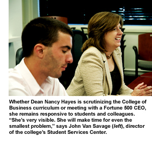 Dean Nancy Hayes smiles in a meeting. Student John Van Savage is seated to her right