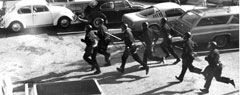 Photograph of police in riot gear running.