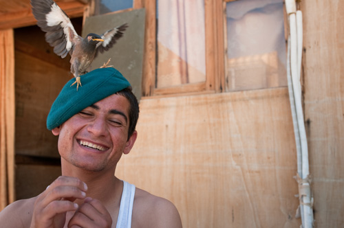 Juma Khan surrenders himself to a boyish grin while a pet bird is perched on his wool beret.