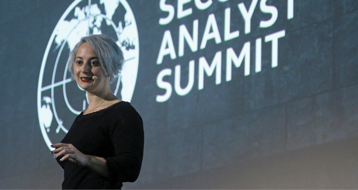 Eva Galperin giving a talk in front of a projection reading 'Analyst Summit'