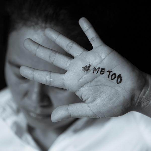 Woman using her hand (with the words #METOO) to block her face