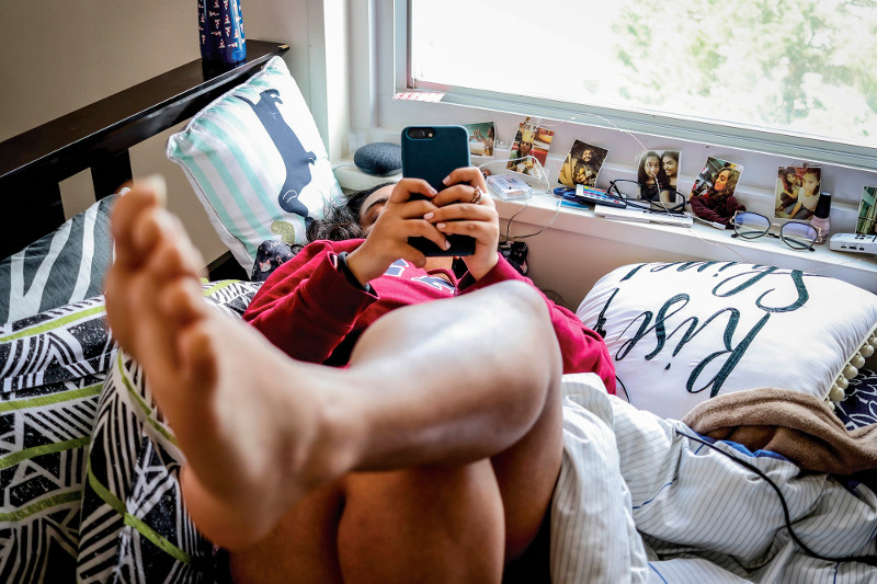 Person using smartphone on a bed