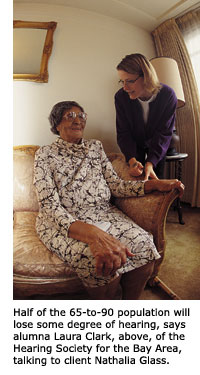 Laura Clark leans in to speak with her client Nathalia Glass who is seated in her living room chair.
