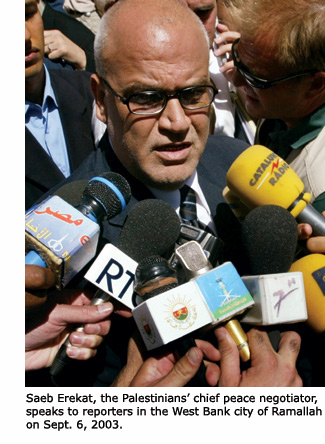 Saeb Erekat, the Palestinians’ chief peace negotiator, surrounded by reporters’ microphones in Ramallah.