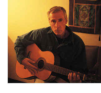 Psychologist Tom Pinkson strumming his guitar in his San Raphael office.