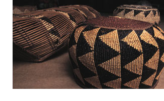 A photo of several woven baskets, black with tan triangles. These are repatriated ceremonial artifacts from a California Indian tribe.