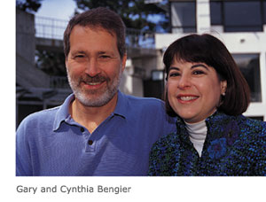 Gary and Cynthia Bengier, husband and wife, stand together smiling on the main plaza of the Cesar Chavez Student Center.