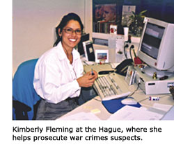 A smiling alumna, Kimberly Fleming sits at her desk at The Hague where she helps prosecute war crimes suspects.