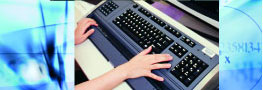 A close-up shot of a student's hands on a Braille keyboard.