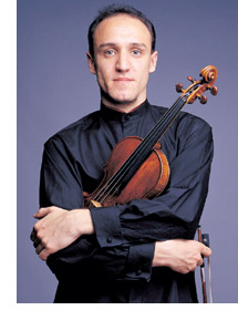 Music Professor Jassen Todorov stands holding his violin and bow.