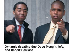 Two debaters, Doug Mungin and Robert Hawkins, standing next to each other gesturing with their hands as they speak.