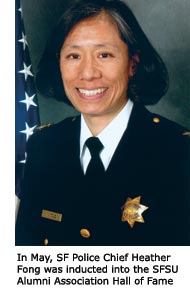 Alumna Heather Fong smiles in her police uniform next to an American flag.