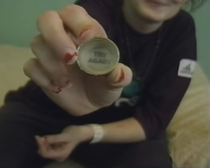 Tracey Helton Mitchell holds up a bottle cap that reads "try again" in a screen capture from a 1999 documentary