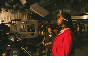 A close-up shot of a young female student listening to the symposium via headphones behind the scenes.