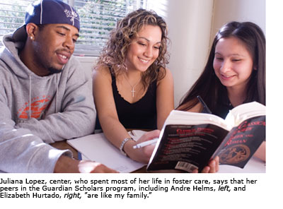 Three Gaurdian Scholars studying together in the library, each one looks on at the same book held by the student in the center, Juliana Lopez.