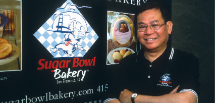 Andrew Ly stands in front of a sign for his Sugar Bowl Bakery
