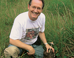 Proessor Dennis Desjardin holds a clump of manuer with a mushroom.