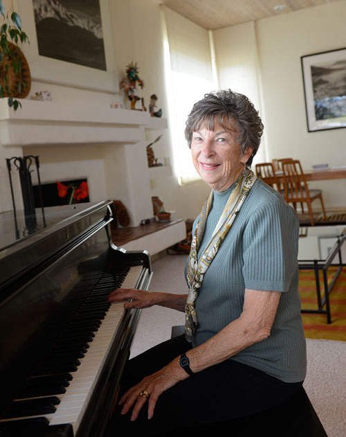 Anne Adams Helms smiling in her home with a piano in front of her