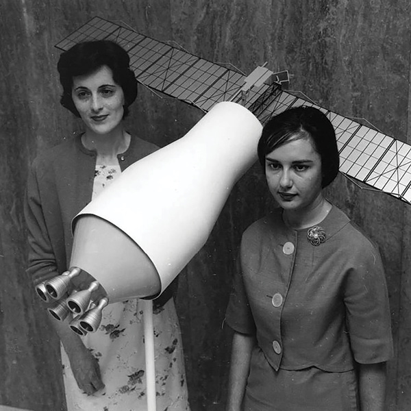 Vintage black and white photo of two female scientists holding a model satellite