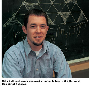 Alumnus Seth Sullivant smiles in front of a blackboard which features an equation he recently solved