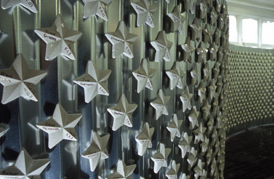 A horizontal magnetized silver wall with many white porcelain stars affixed to it