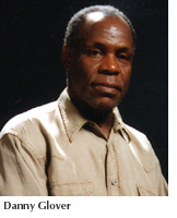Actor and alumnus Danny Glover on a darkened stage with a serious expression
