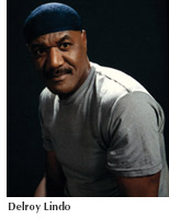 Actor and alumnus Delroy Lindo on a darkened stage with a serious expression