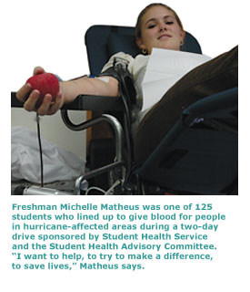 Student Michelle Matheus reaches out to squeeze a red ball while she gives blood in the student health center
