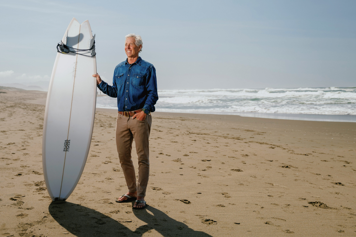Alumnus Bill Martin at Ocean Beach with a surfboard