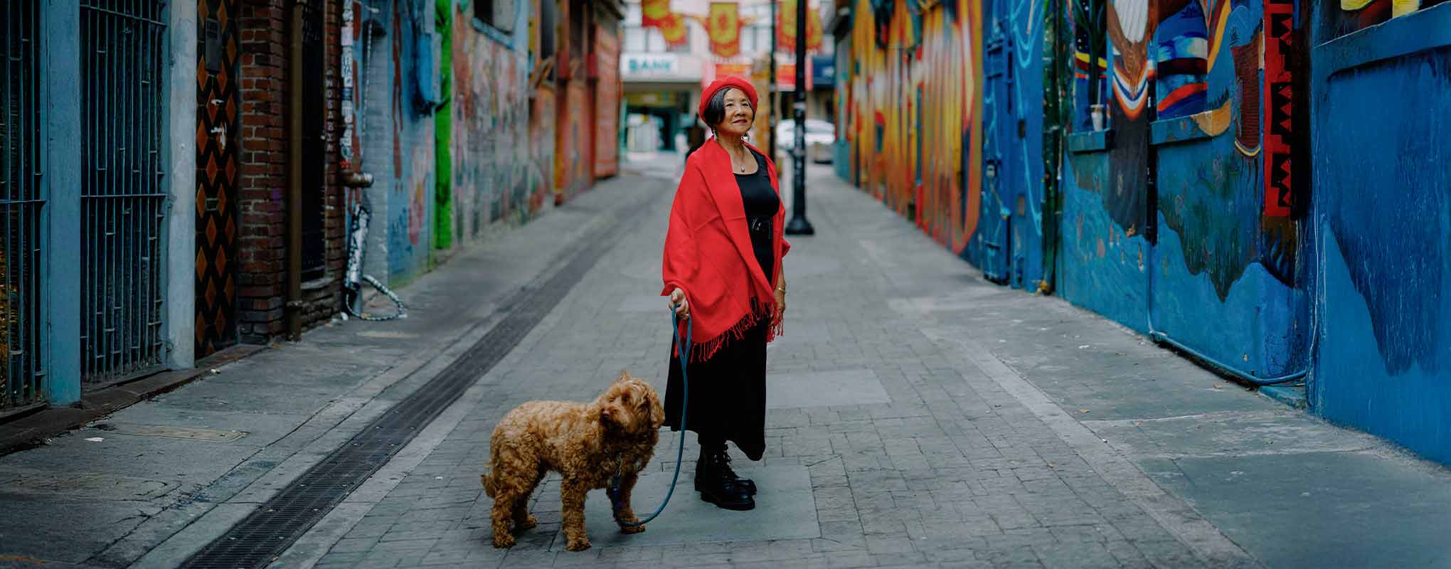Genny Lim and her dog stop in the middle of a chinatown alleyway