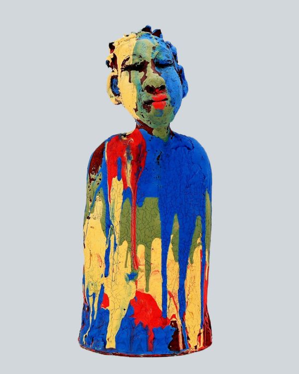 Glazed terracotta sculpture representing a child that is drenched in blue, green, red and yellow paint