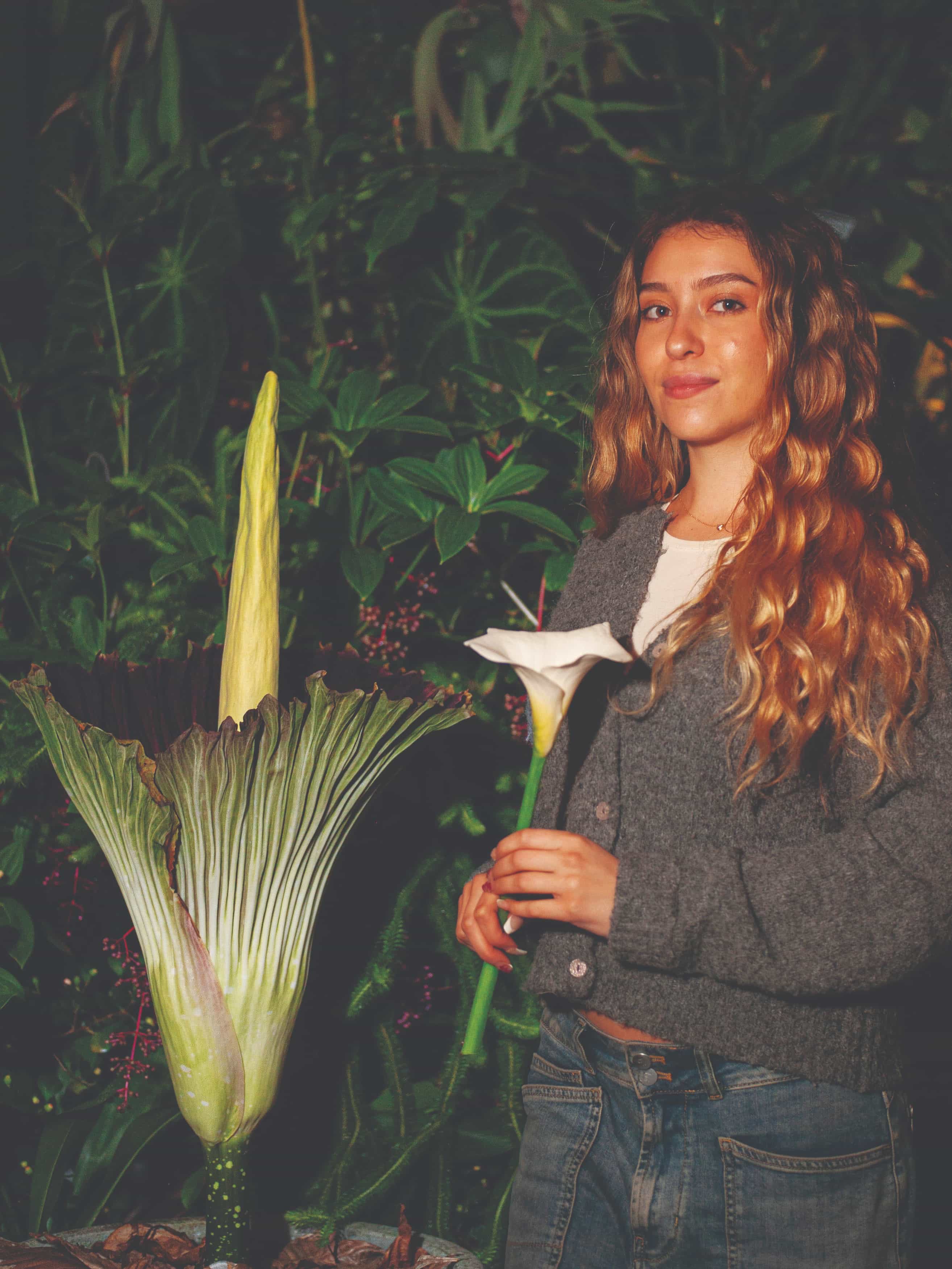 SFSU Student in the campus green house next to the blossoming corpse flower
