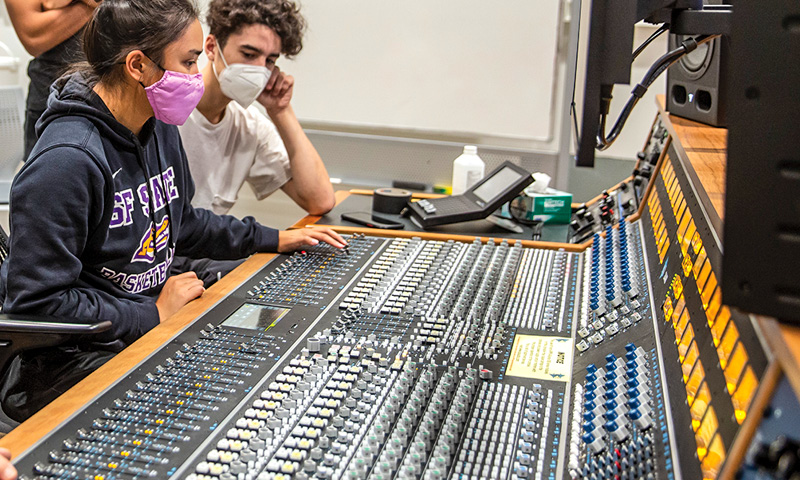 Two SFSU students sitting in front of audio/visual equipment