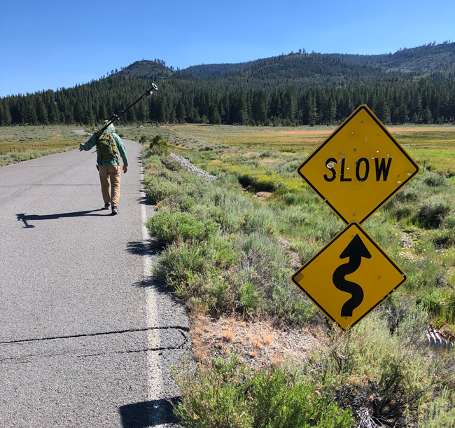 Raymond LeBeau walking on the road with a traffic slow curve sign in the foreground