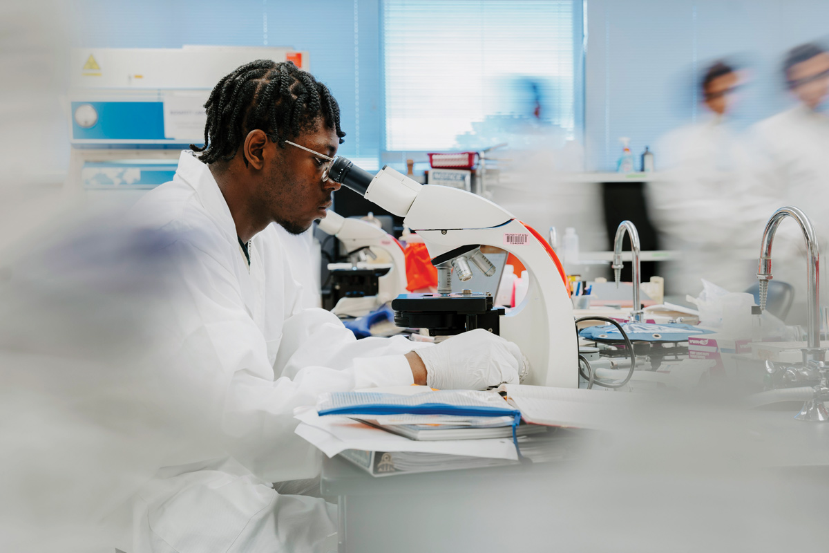 a scientist in a lab coat looking through a microscope