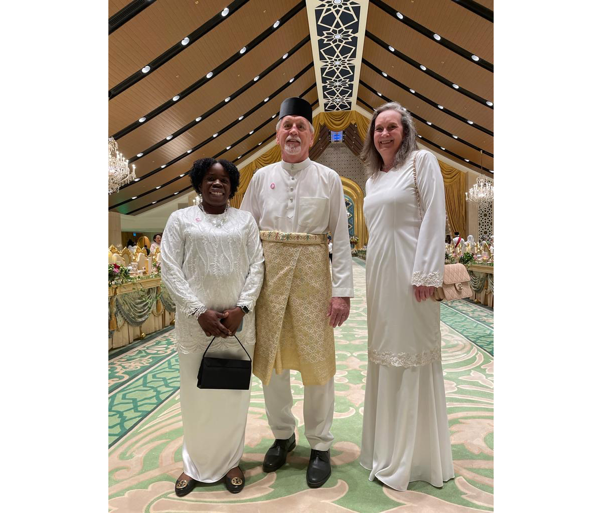 McClelland in a white gown with two friends in cultural garb