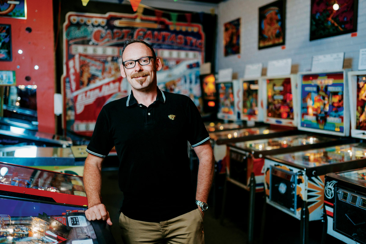 Evan Phillippe standing next to an arcade of pinball machines