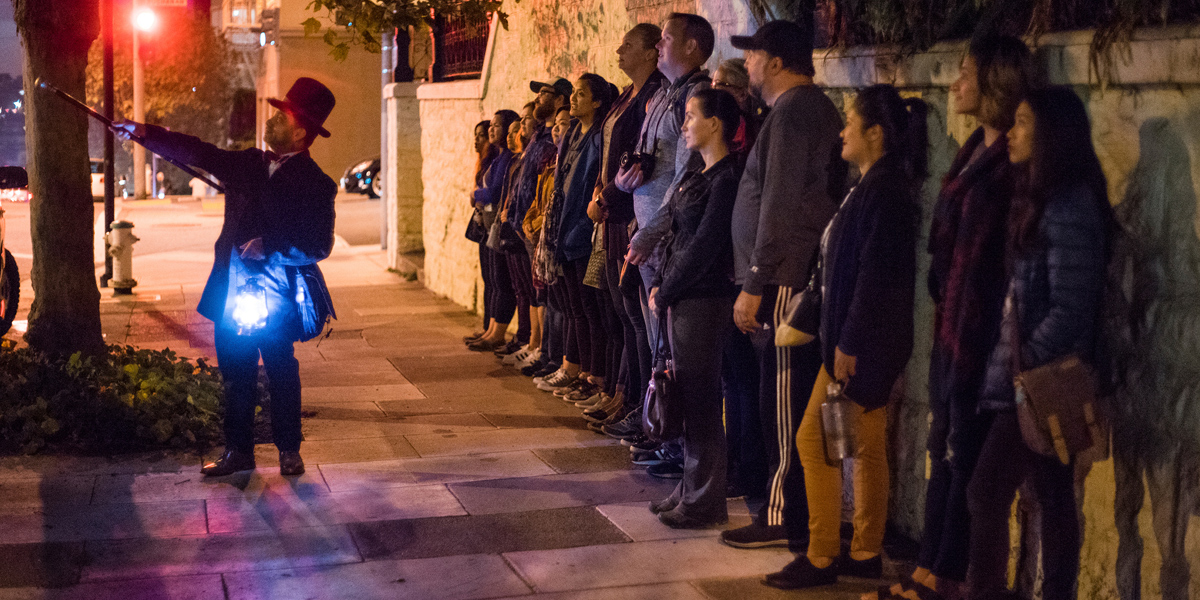 Christian Cagigal leading a ghost tour with a group of people observing