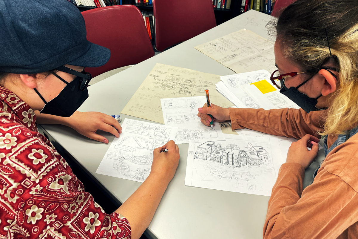 Two students designing and drawing a comic book layout